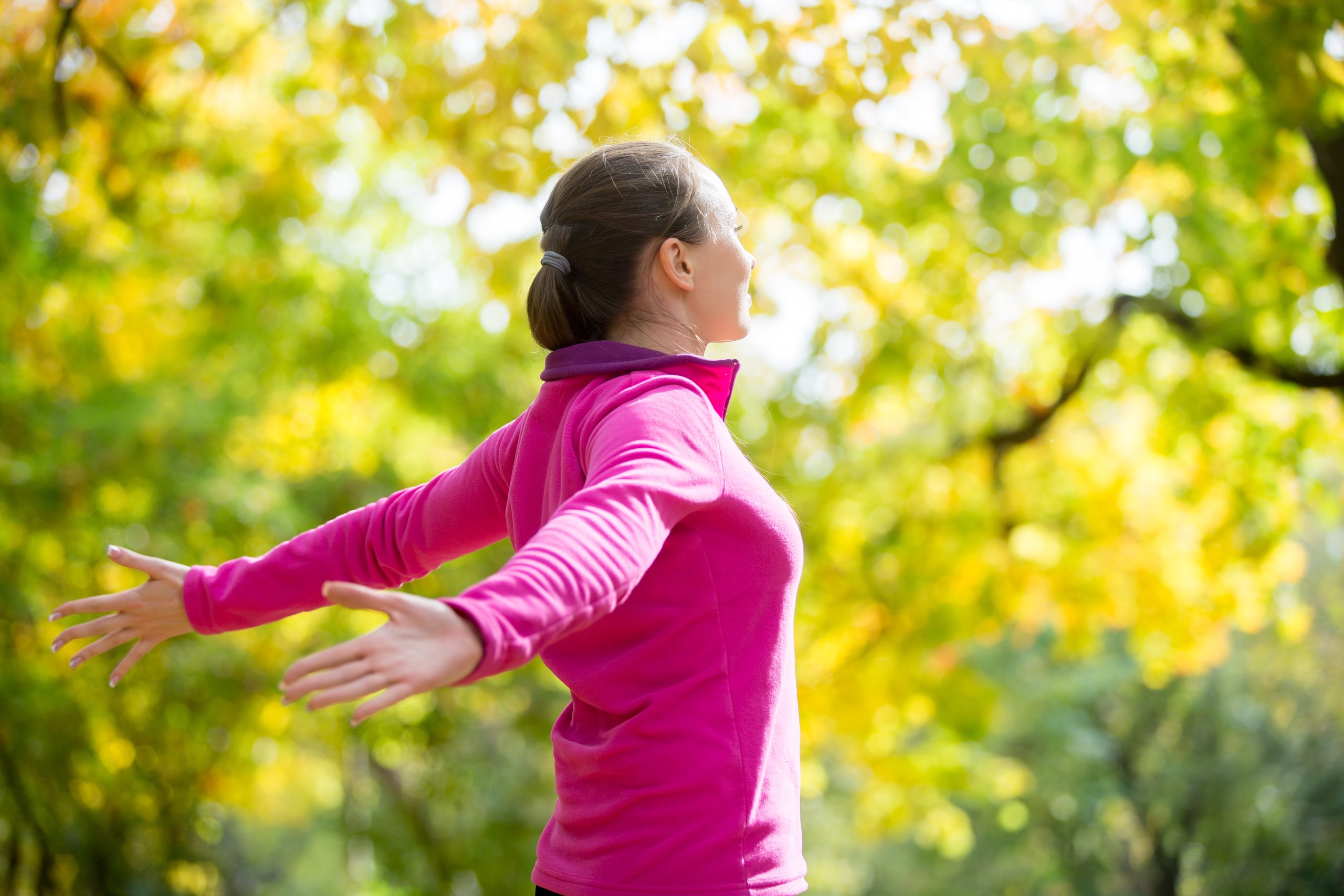 Portrait of an attractive smiling woman outdoors in a sportswear, her hands outstreched. Indian summer. Concept photo, side view
